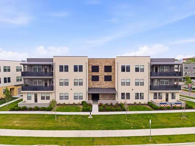 Modern multifamily building featuring a light stucco facade with stone accents and dark metal railings