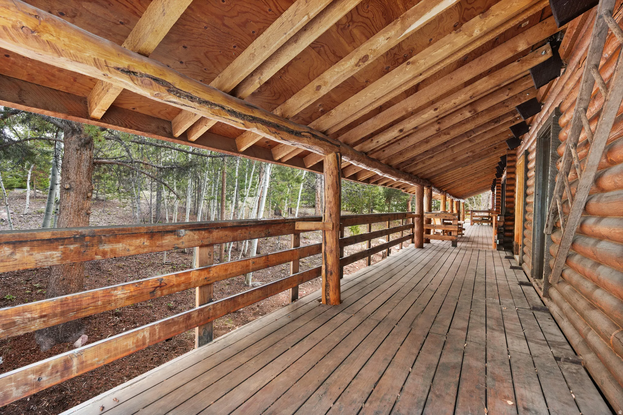 Expansive covered porch featuring wood-finish flooring and a log railing