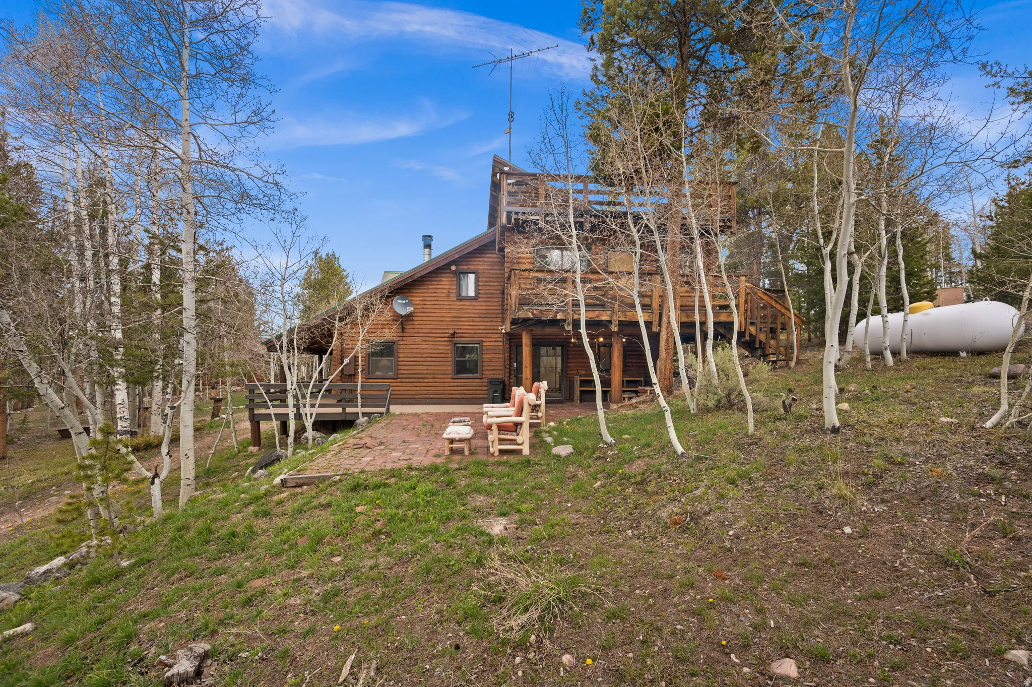 Wood-sided property featuring multiple levels, an elevated deck, and a lower-level patio