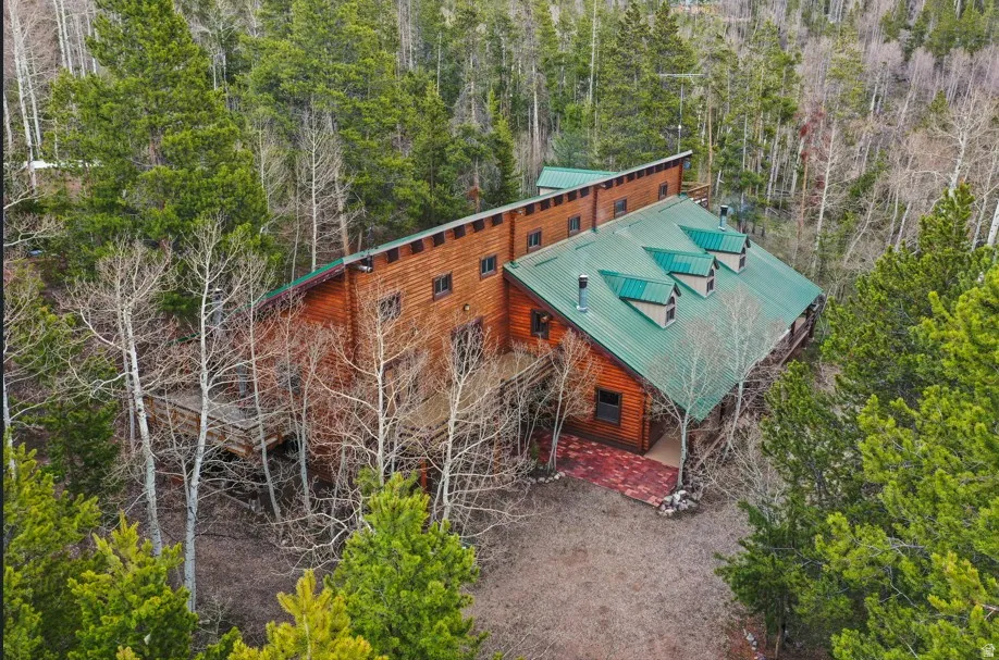Wood-sided residence featuring a green metal roof with three dormers