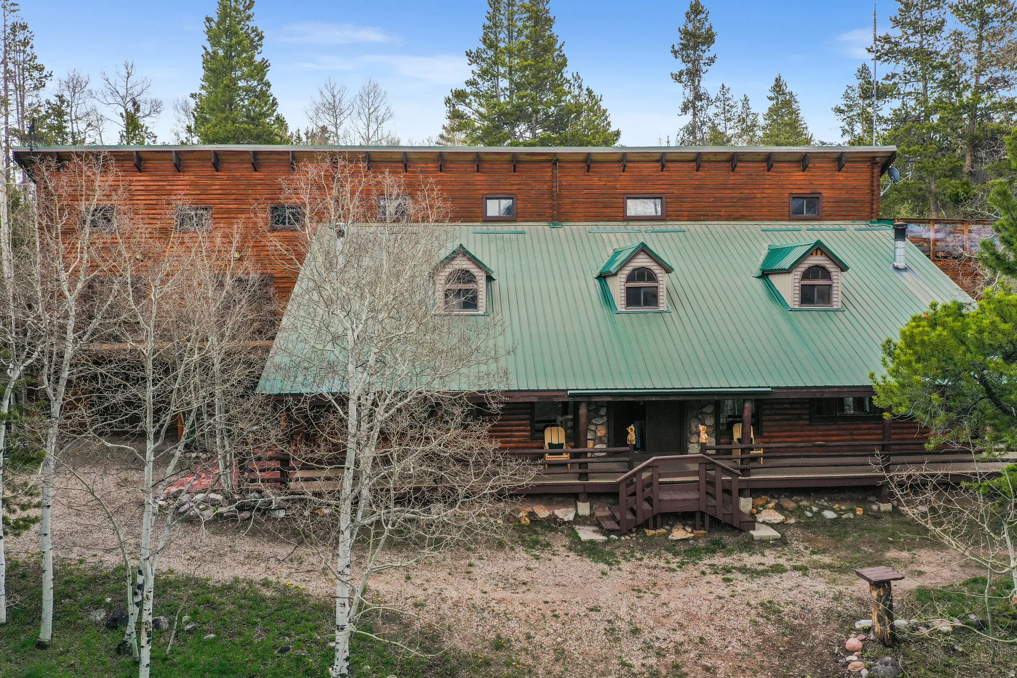 Log-style exterior with a green metal roof and multiple dormer windows
