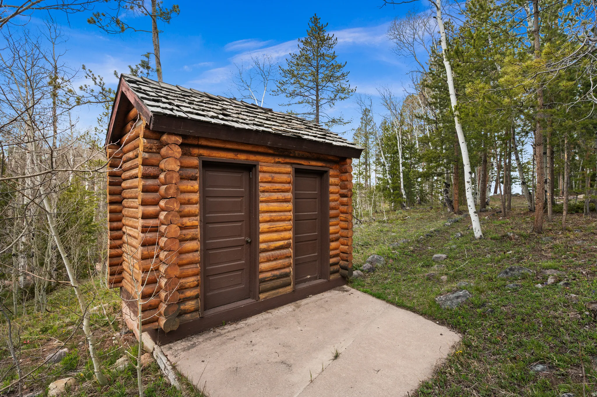 Log cabin structure with two entry doors and a wood shake roof