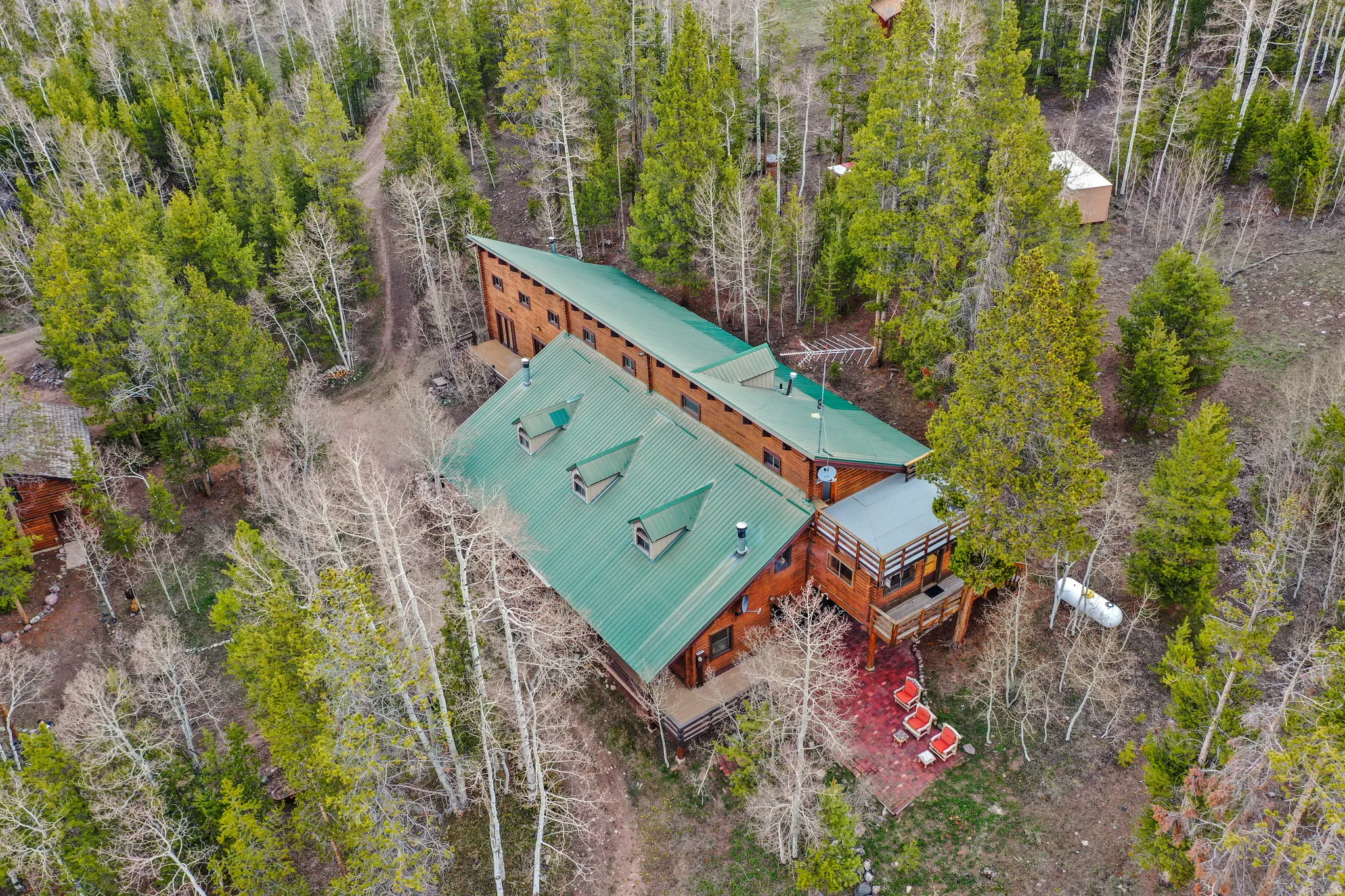 Expansive property featuring a multi-level wood-sided structure with a green metal roof