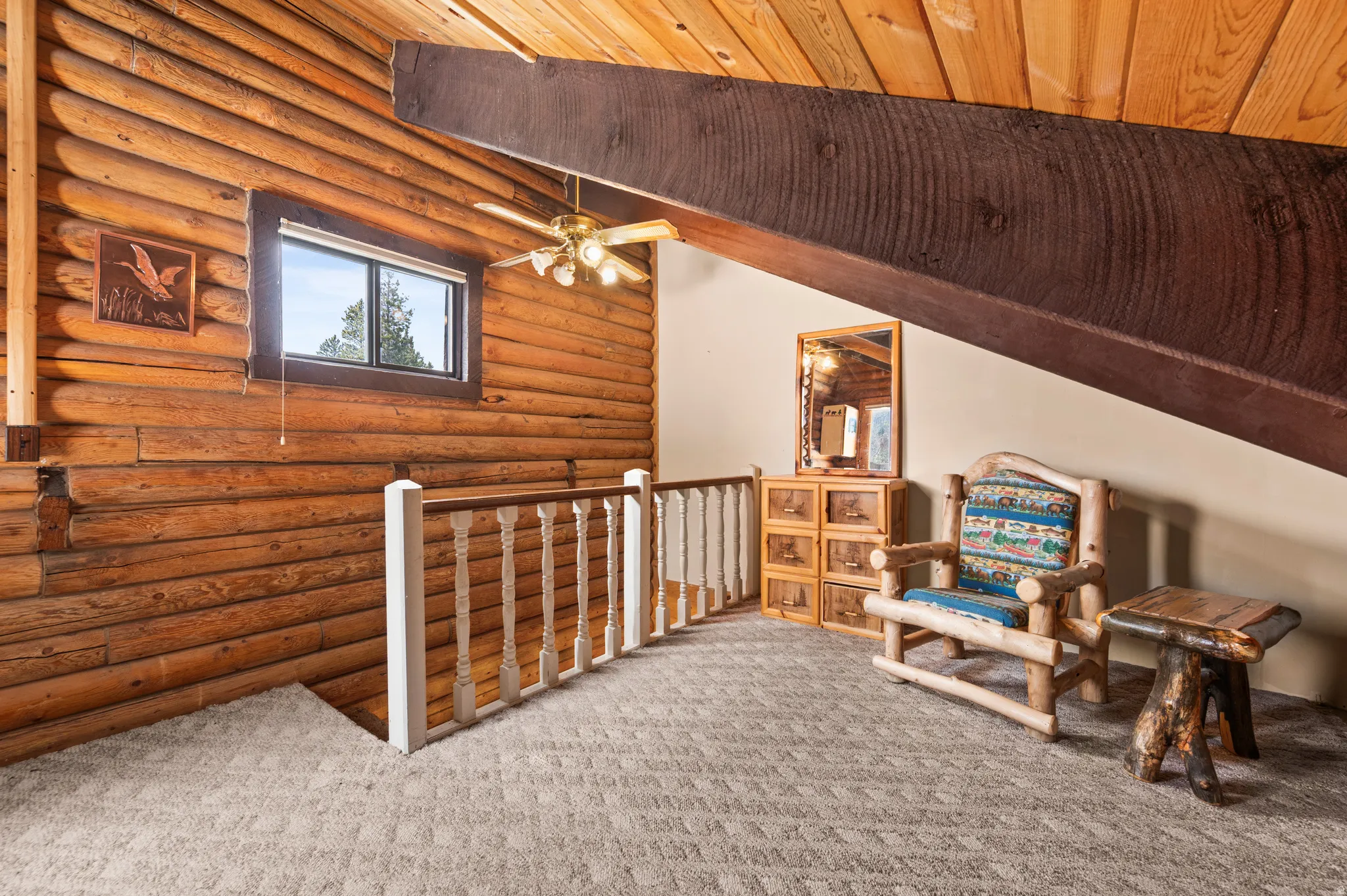 Loft area featuring log walls, an exposed wood beam ceiling, a ceiling fan with light fixture, and plush carpet flooring