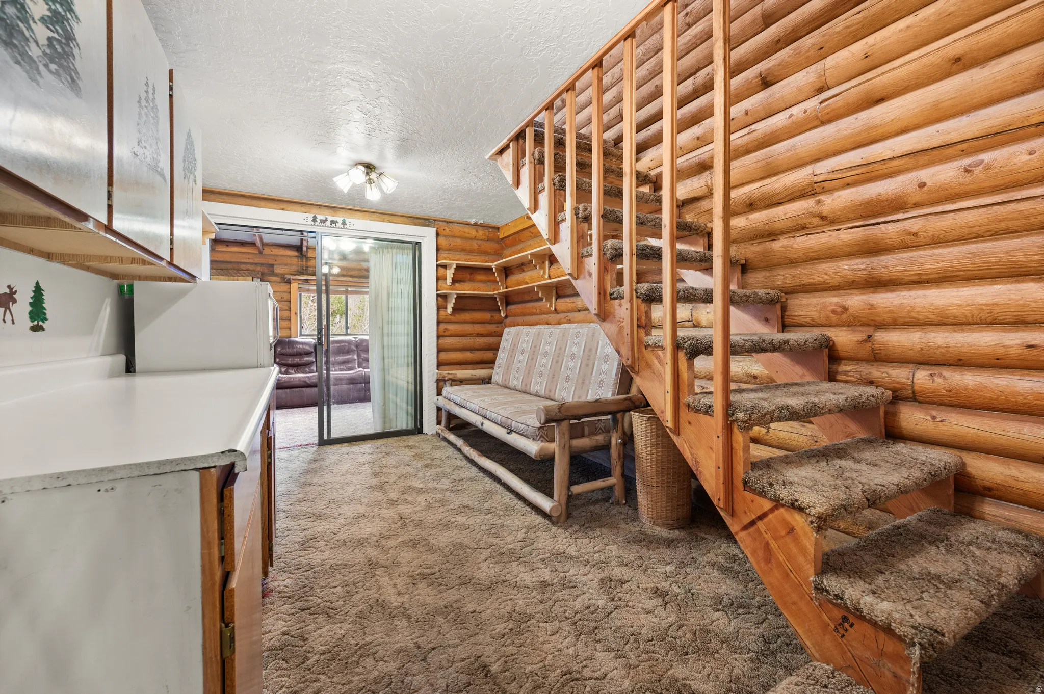Natural wood log walls featuring a staircase with carpeted treads and a wooden railing