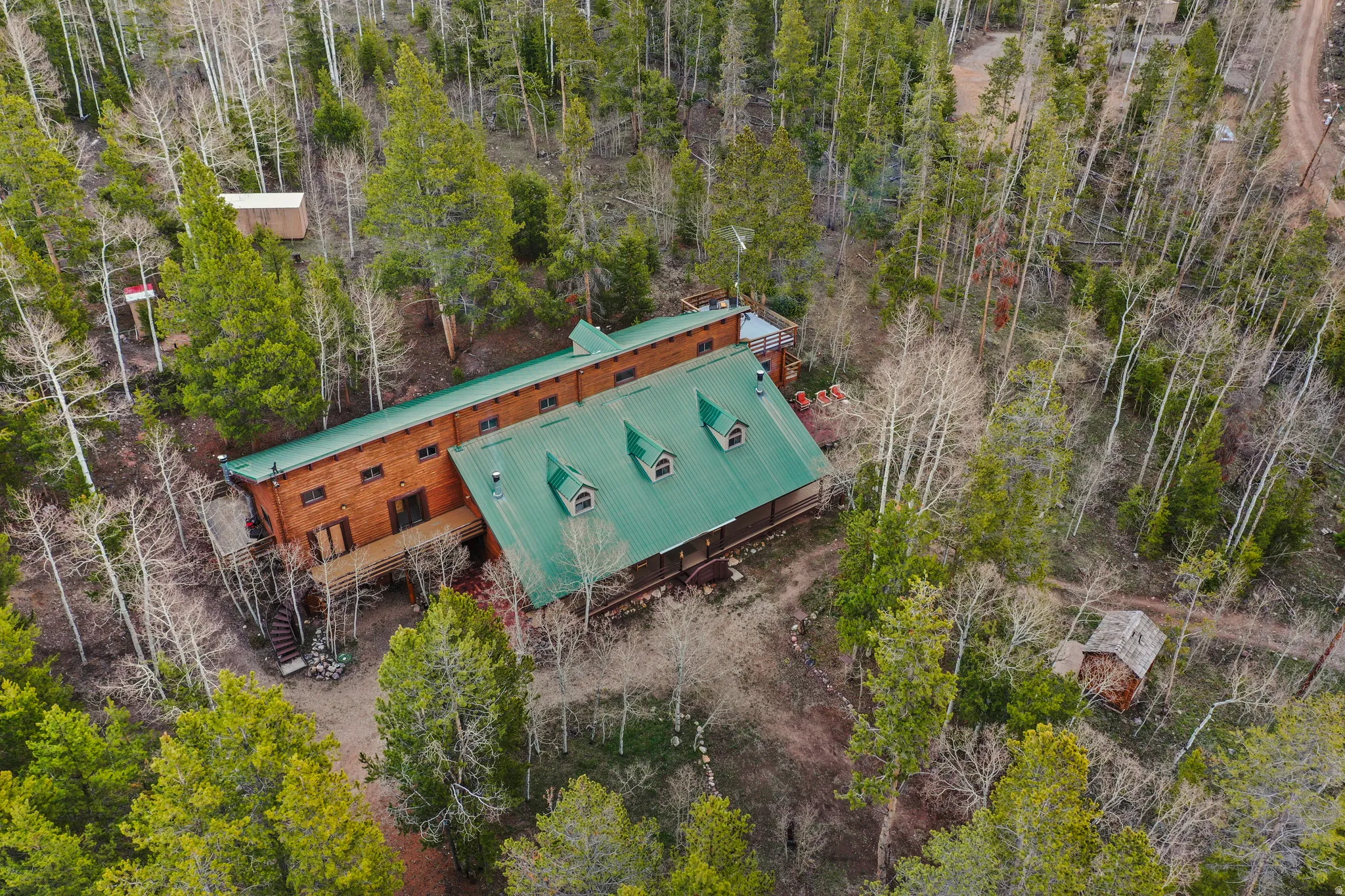 Wood-sided home with a green metal roof, surrounded by mature trees