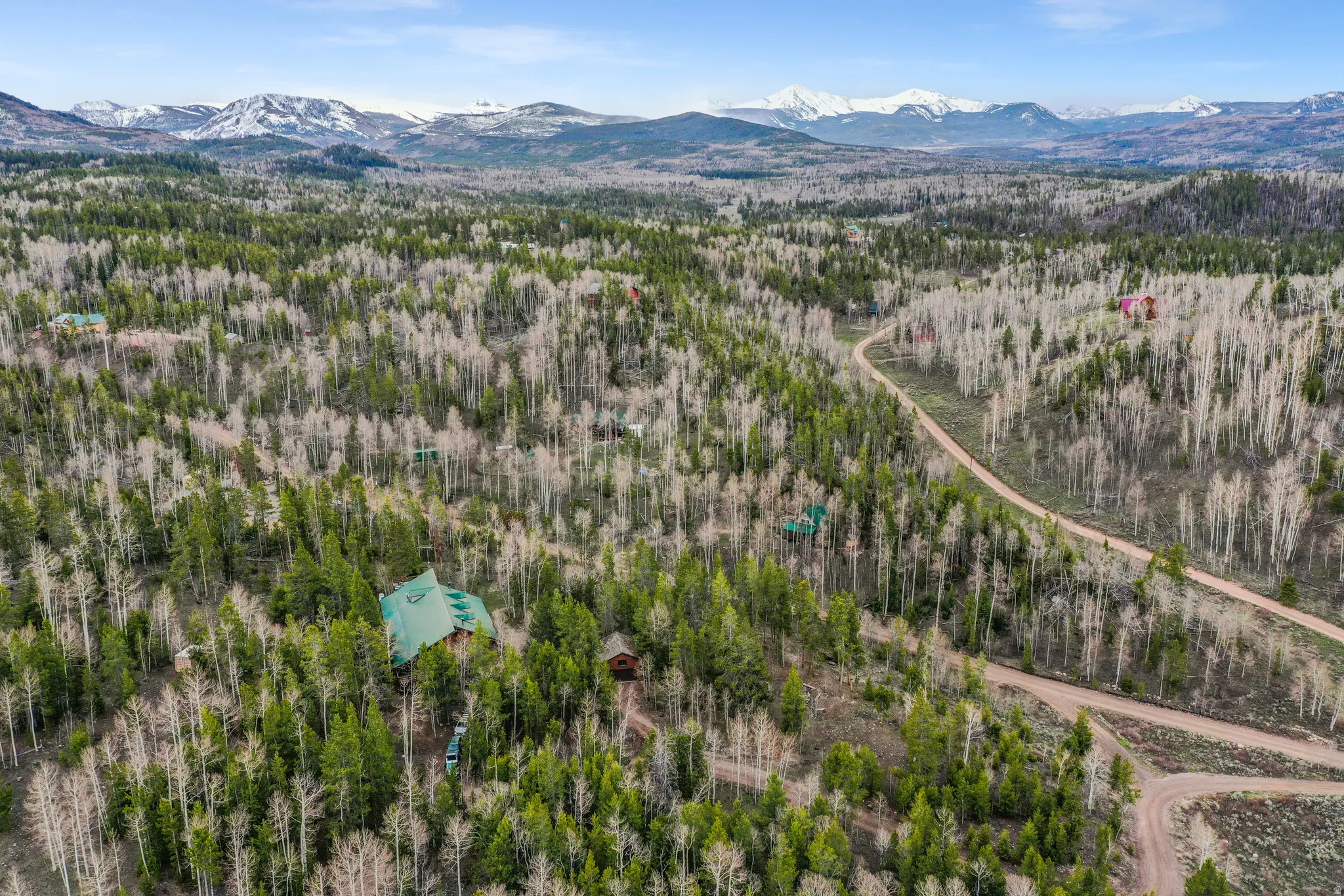 Mountain property featuring a distinctive green roof and surrounding evergreen and deciduous trees