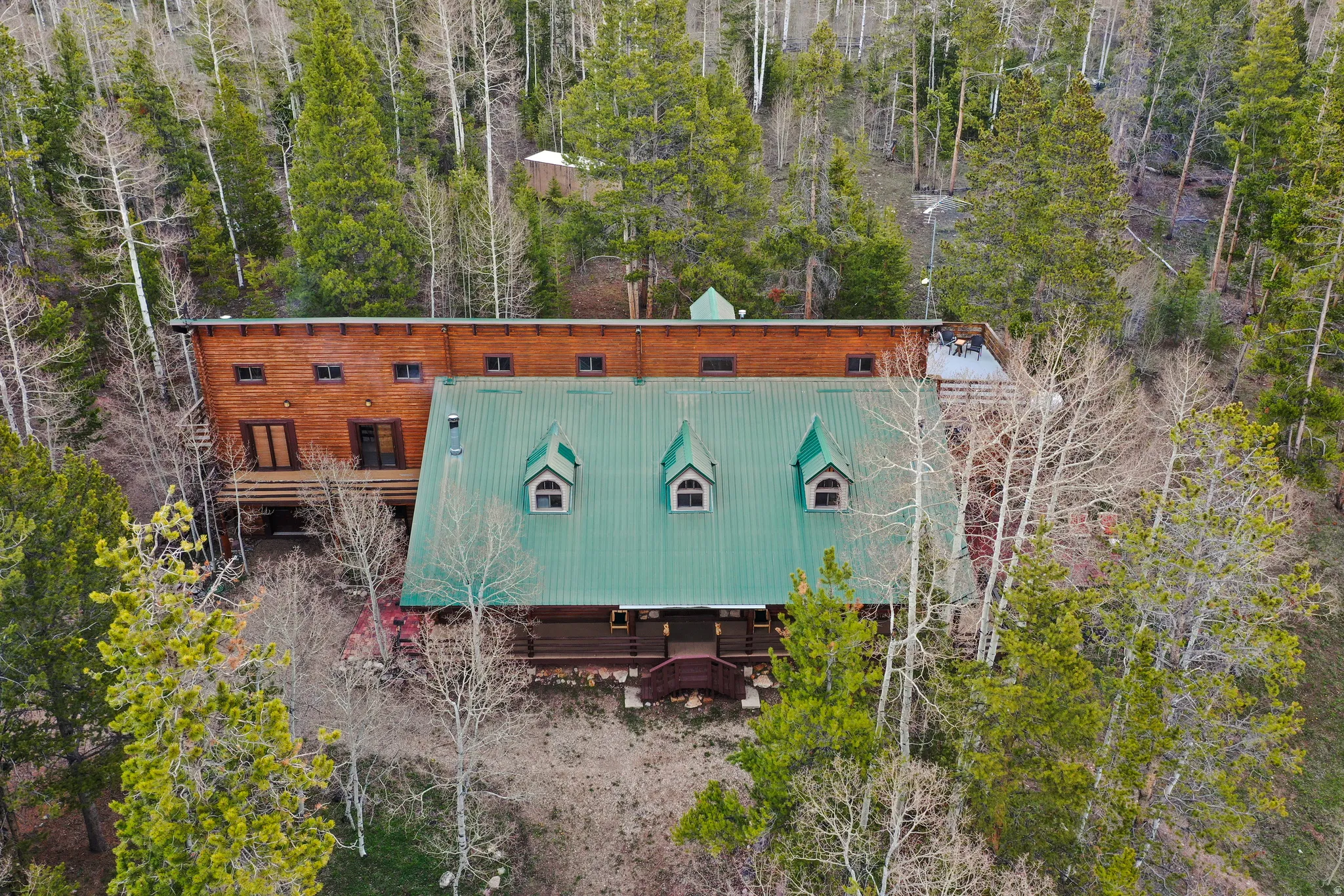 Wood-sided residence featuring a green metal roof with dormer windows, multiple balconies, and an elevated deck