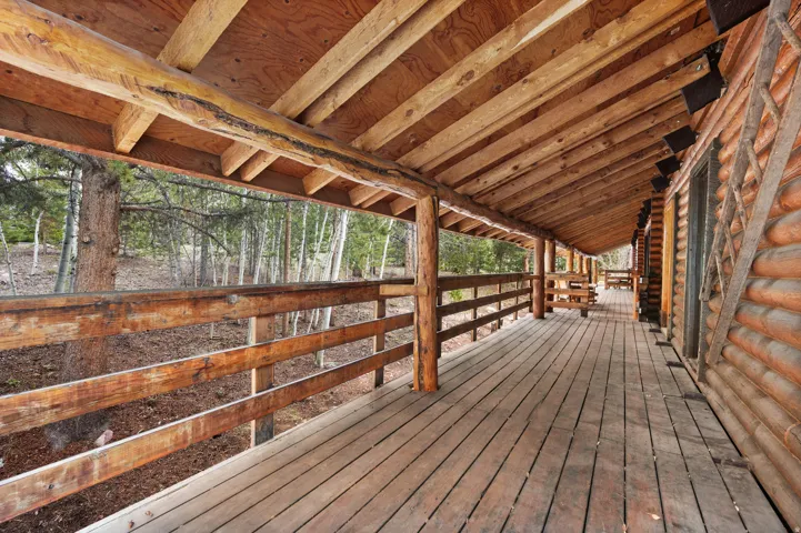 Expansive covered porch featuring wood-finish flooring and a log railing
