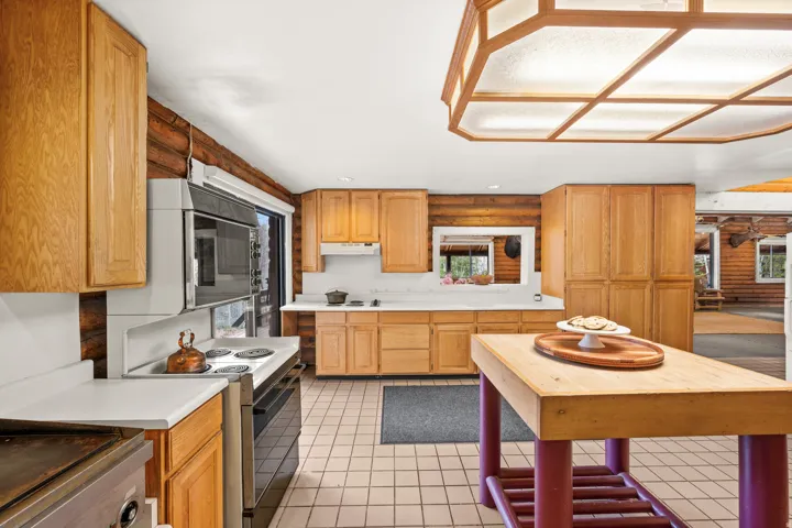 Kitchen featuring light wood cabinetry, white countertops, built-in oven, and a center island with a wood top
