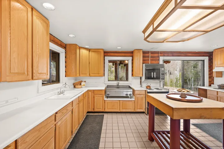 Kitchen featuring light wood cabinetry, white countertops, built-in appliances, recessed lighting, and a large sliding glass door