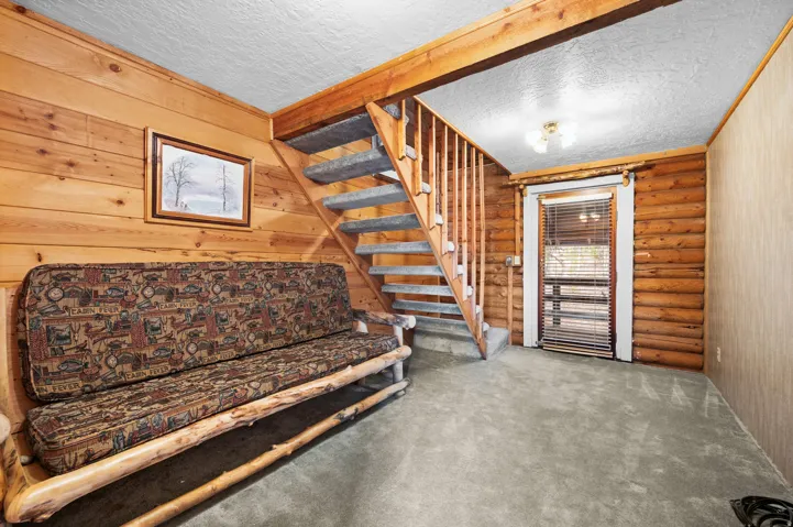 Interior space featuring a carpeted staircase with wood railings, log walls, wood-paneled walls, and carpet flooring