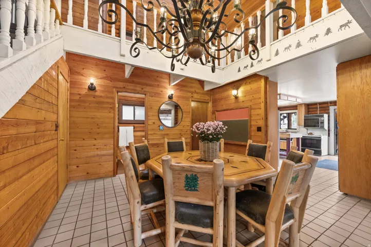 Dining area featuring natural wood paneling, a large decorative chandelier, and a tiled floor