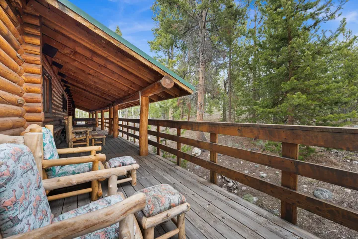 Expansive covered wood porch featuring a log cabin exterior, exposed wood ceiling, and wood railing