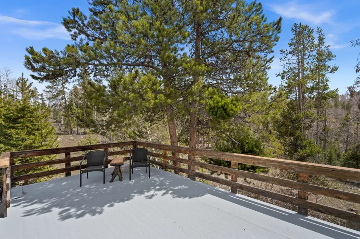 Expansive outdoor deck with natural wood railing overlooking a pine forest