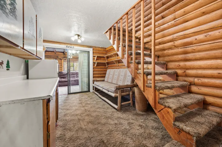 Natural wood log walls featuring a staircase with carpeted treads and a wooden railing