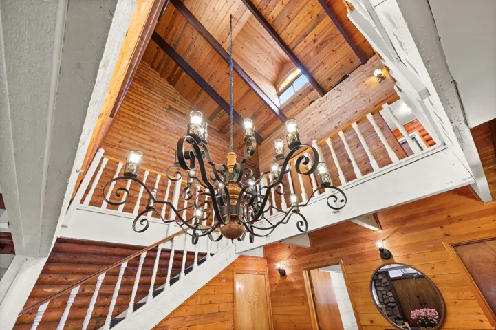Vaulted wood-paneled ceilings featuring exposed beams and an iron chandelier