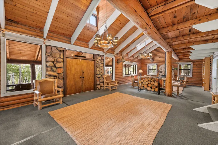 Vaulted wood-paneled ceilings with exposed beams, log walls, stone accents, and large windows