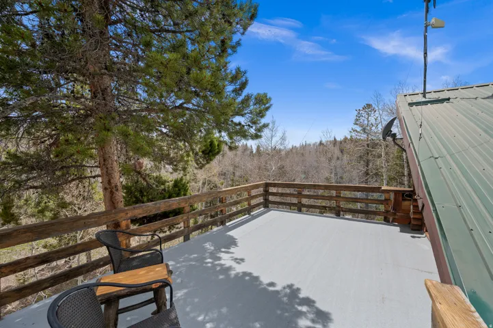 Expansive outdoor deck featuring a gray surface and rustic wood railing