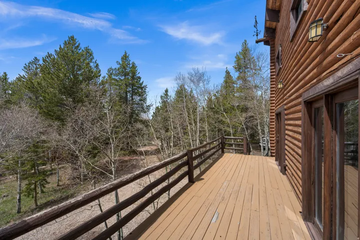 Expansive outdoor deck featuring wood flooring and a rustic wood railing