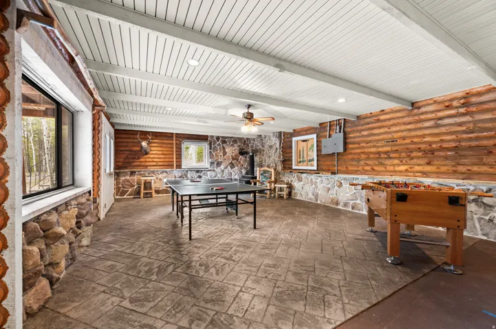 Spacious room featuring wood plank walls, stone accents, and a durable stamped concrete floor