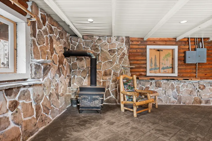 Stone-accented walls featuring a wood-burning stove with metal flue