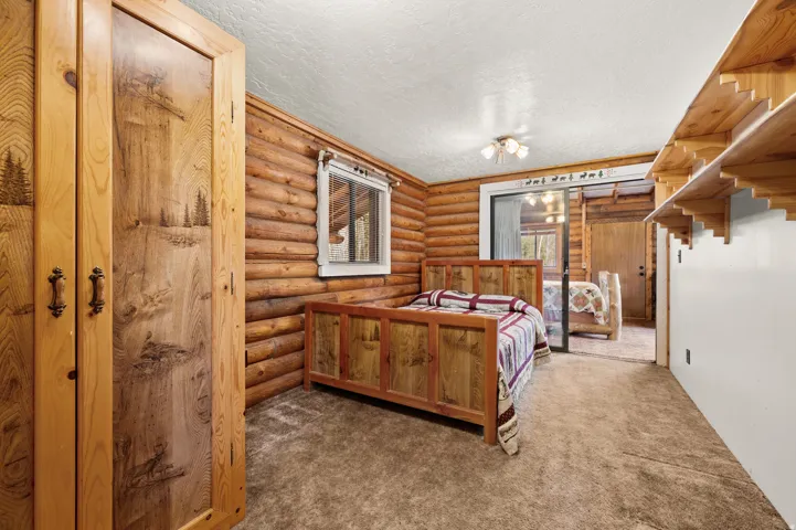 Wood-clad interior featuring log walls, decorative wood-carved armoire, a ceiling-mounted light fixture, and built-in shelving