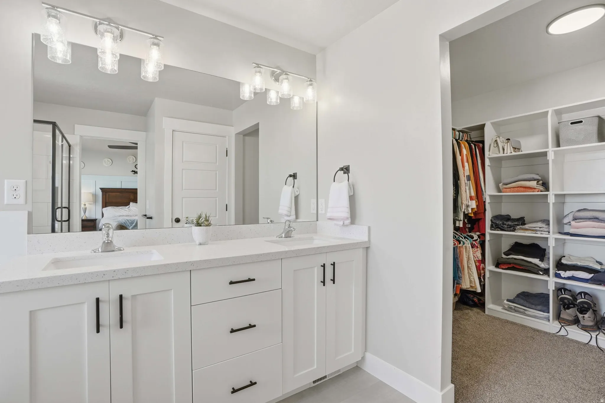 Dual vanity with white cabinetry, integrated sinks, quartz-finish countertop, and matte black hardware