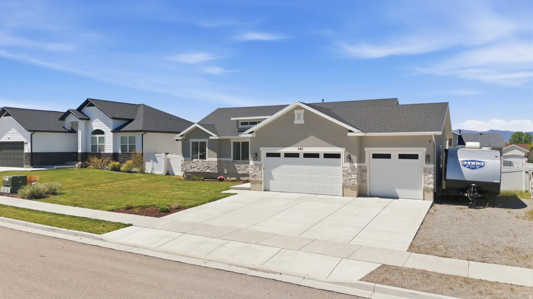 Contemporary single-story residence featuring a two-car garage, an additional single-car garage, and stone accent siding with space for RV