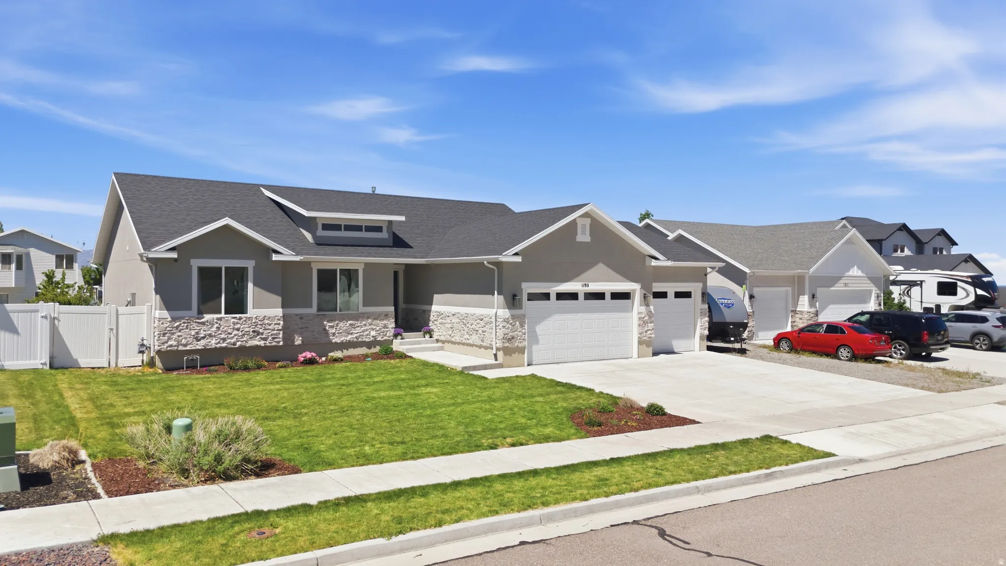 Modern ranch-style residence featuring a gray exterior with stone accents and a dark shingle roof