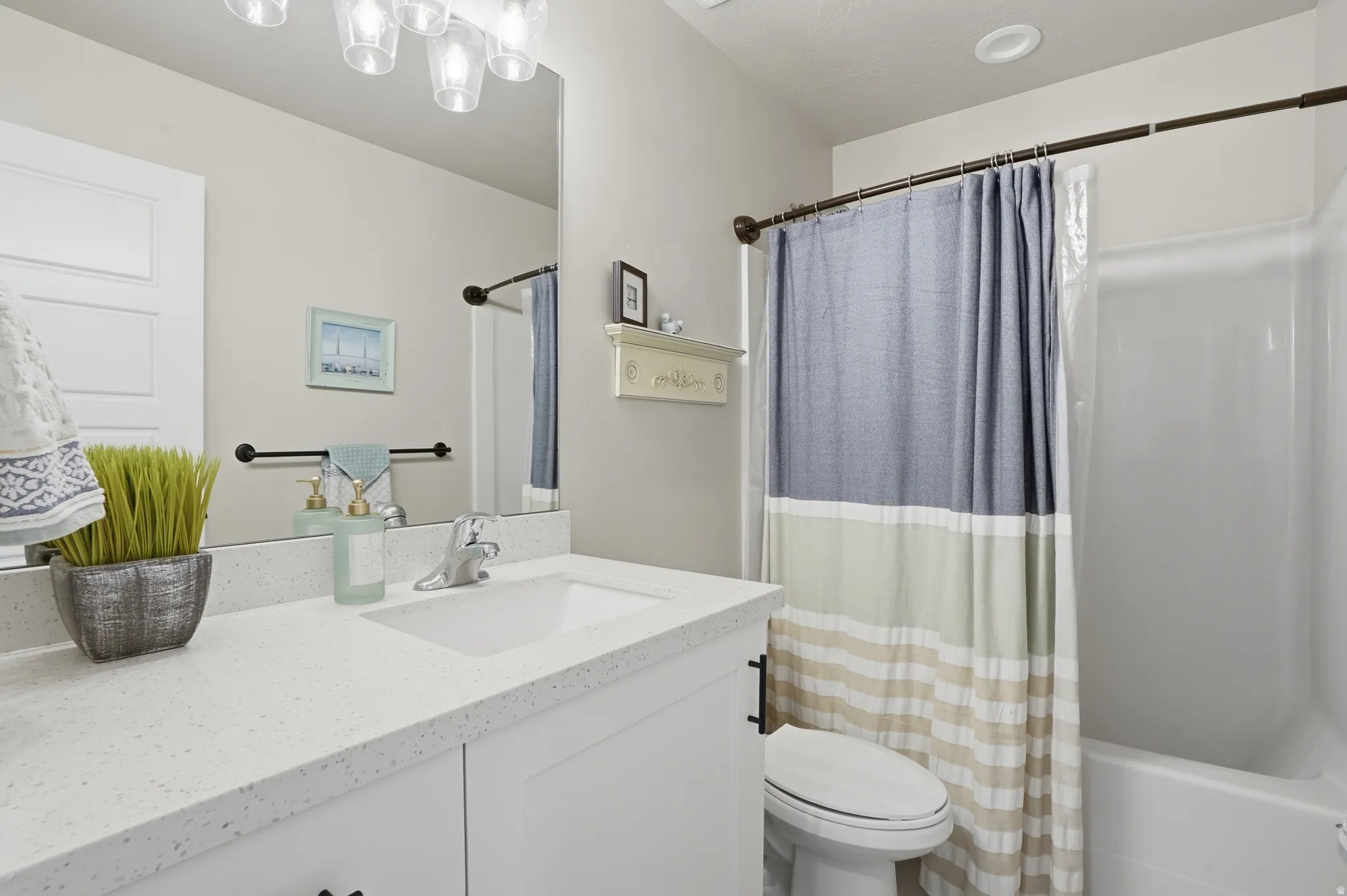 Main bathroom featuring a white vanity with an integrated sink, polished chrome faucet, and speckled countertop