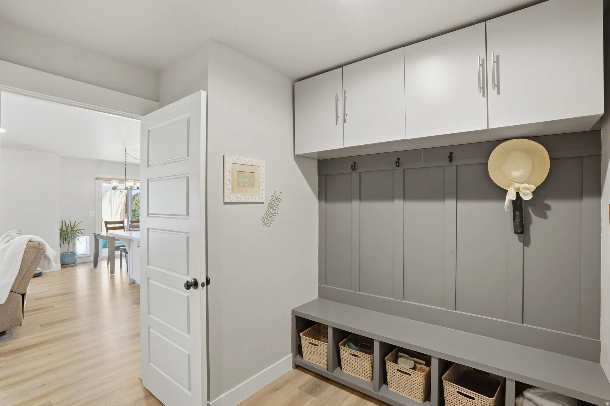Entryway mudroom featuring built-in gray shaker paneling, integrated bench seating with open storage cubbies, and upper white cabinetry with brushed nickel hardware