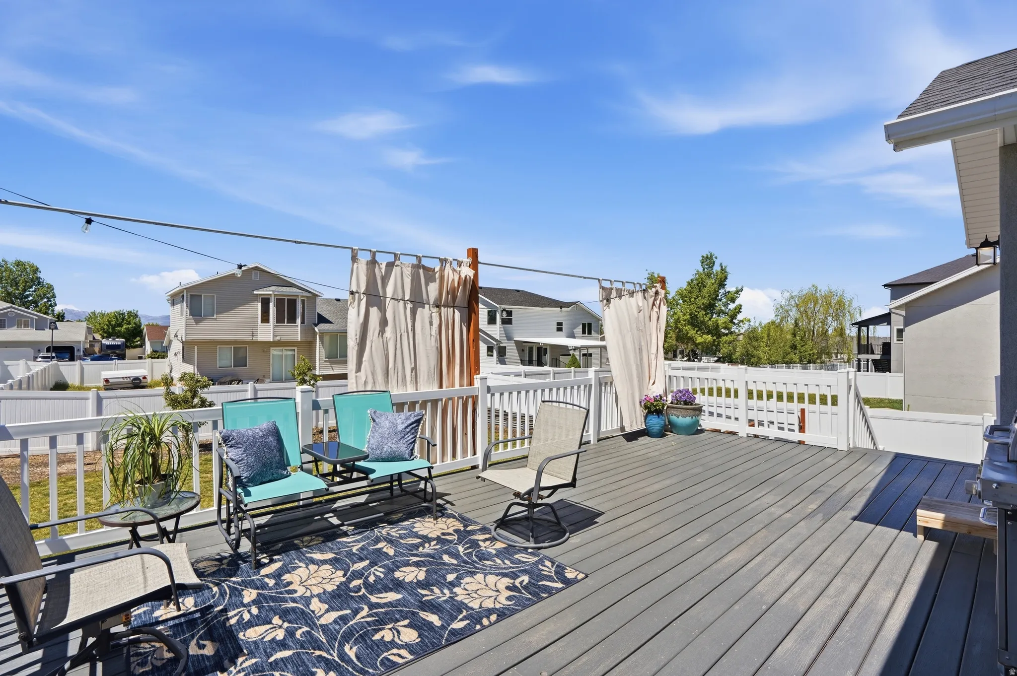 Spacious outdoor deck featuring composite decking, white railing, privacy screens, and exterior lighting
