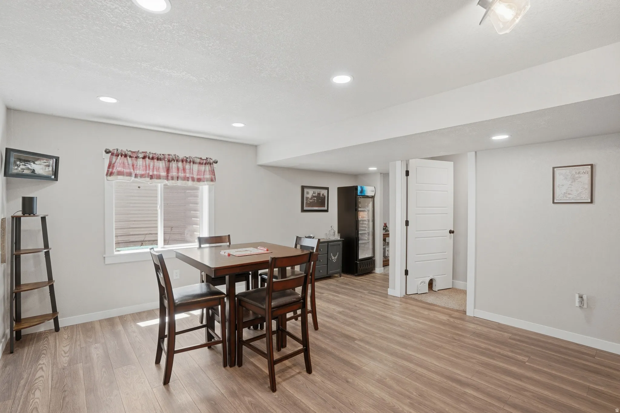 Finished basement space featuring wood-finish flooring, recessed lighting, and a white paneled door