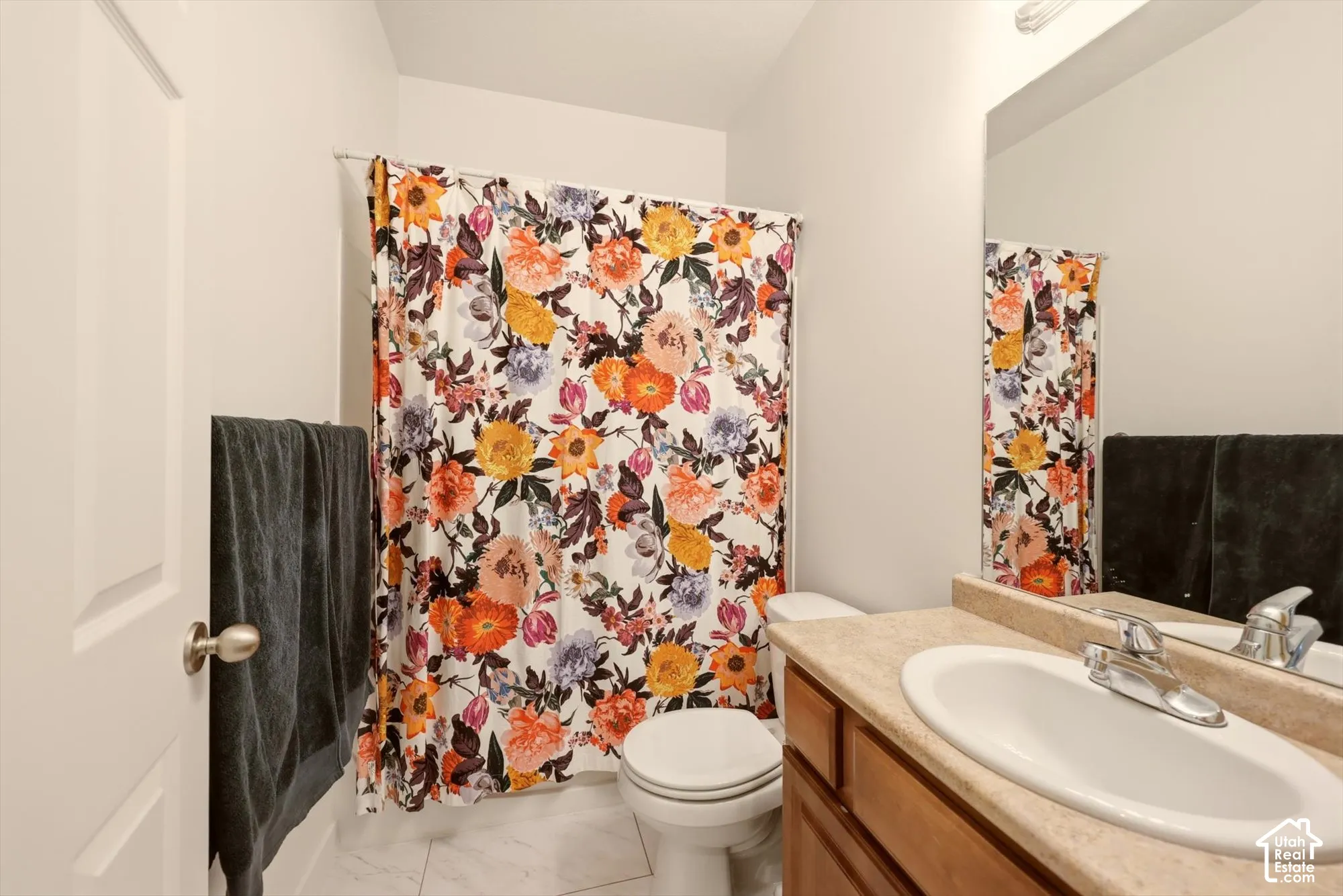 Bathroom featuring a light-toned vanity with an integrated sink, a chrome-finish faucet, and a large mirror