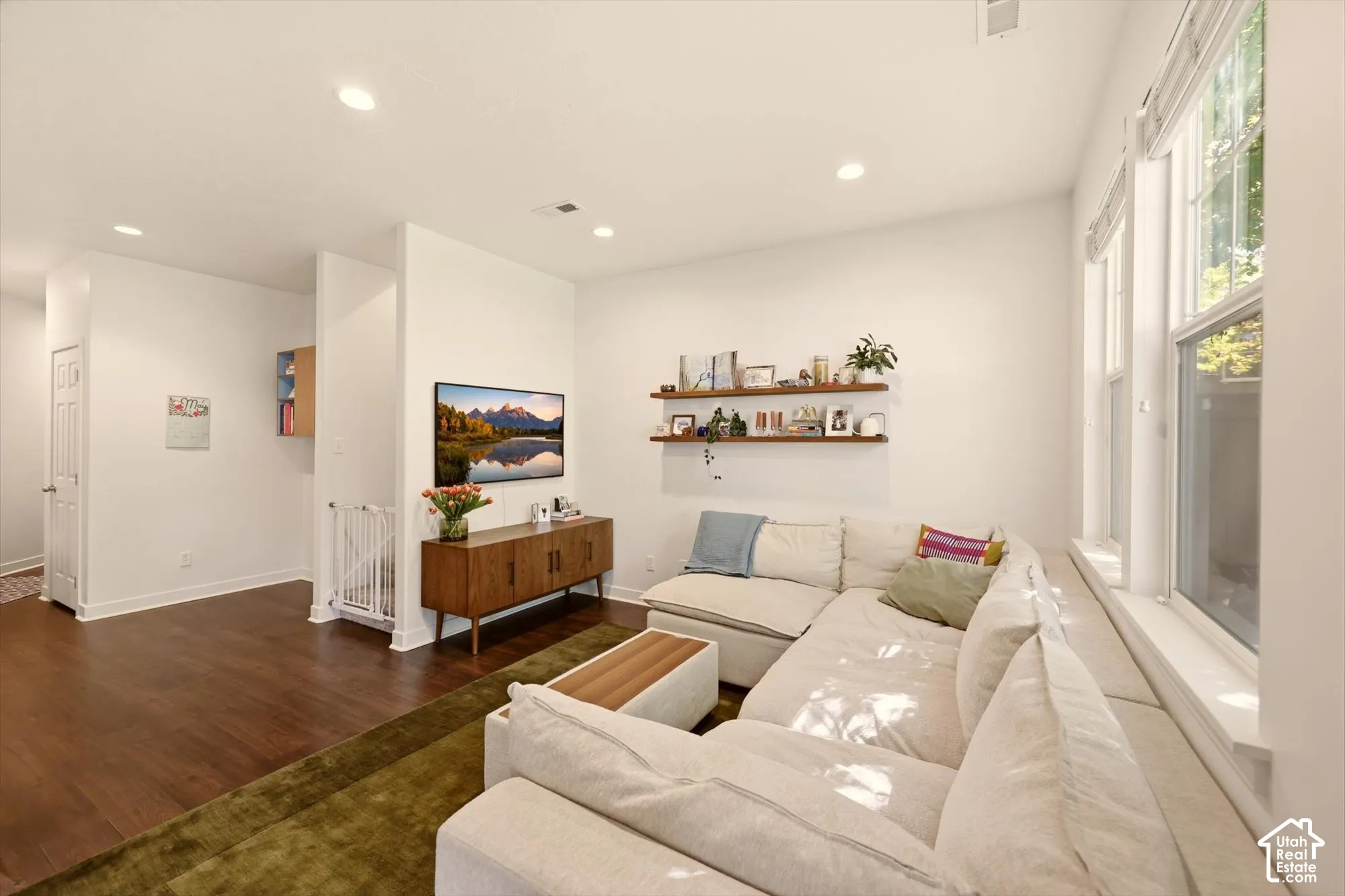 Spacious living area featuring abundant natural light, recessed lighting, wood-finish flooring, and built-in floating shelving