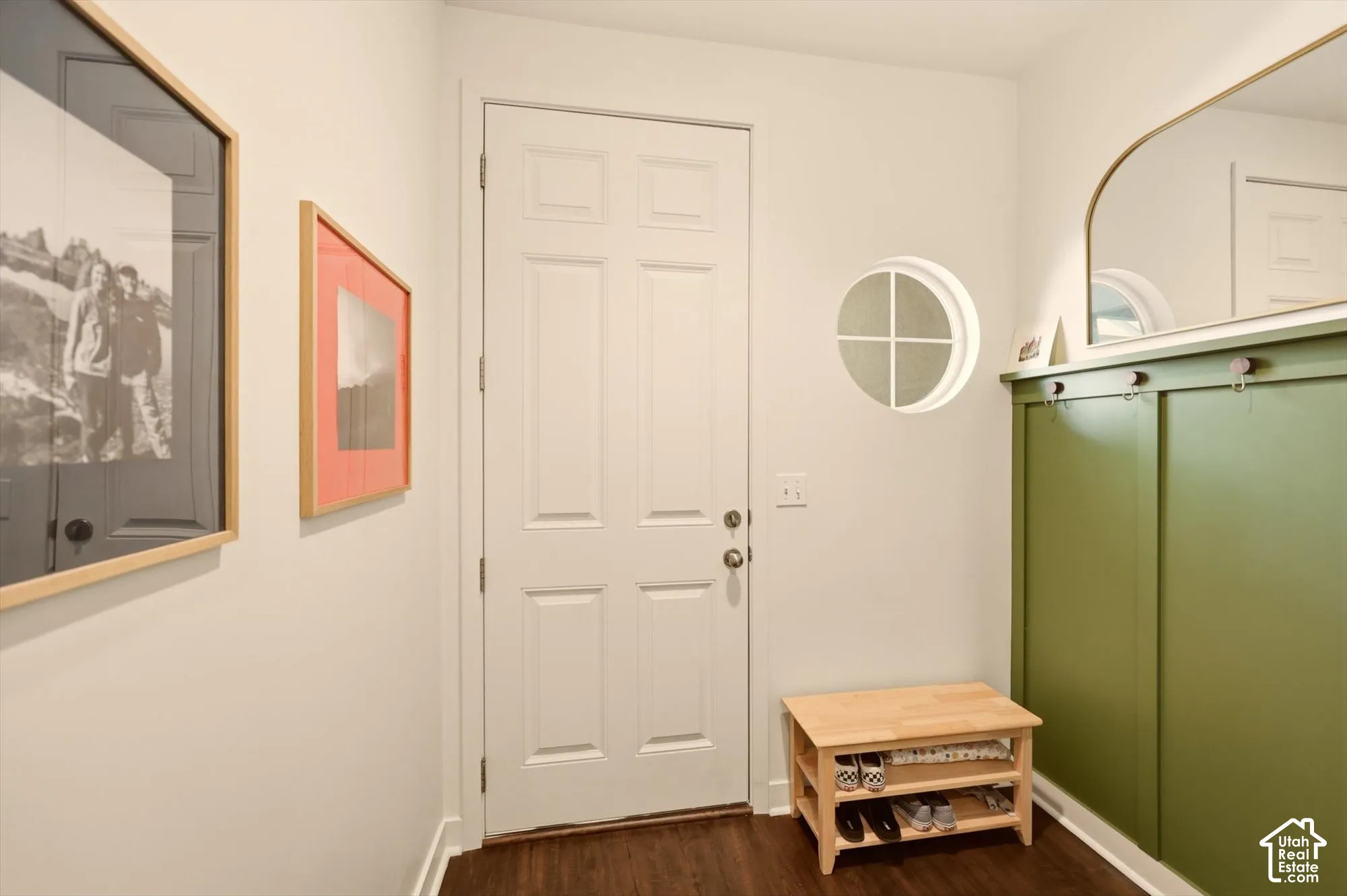Entryway featuring a white paneled door, circular window, built-in green accent paneling, and wood-finish flooring
