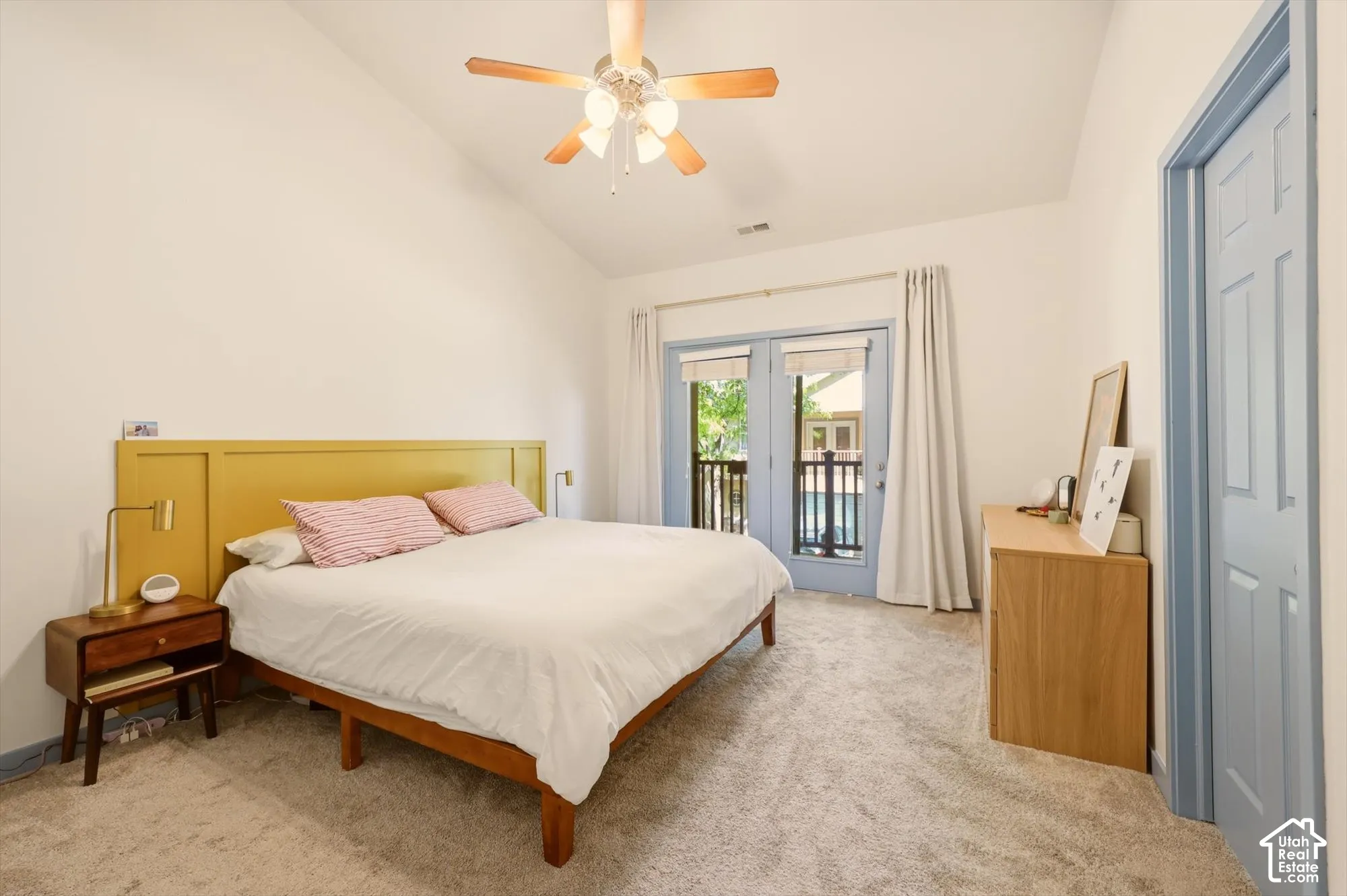 Bedroom featuring vaulted ceilings, light-colored carpeting, and a ceiling fan with integrated lighting