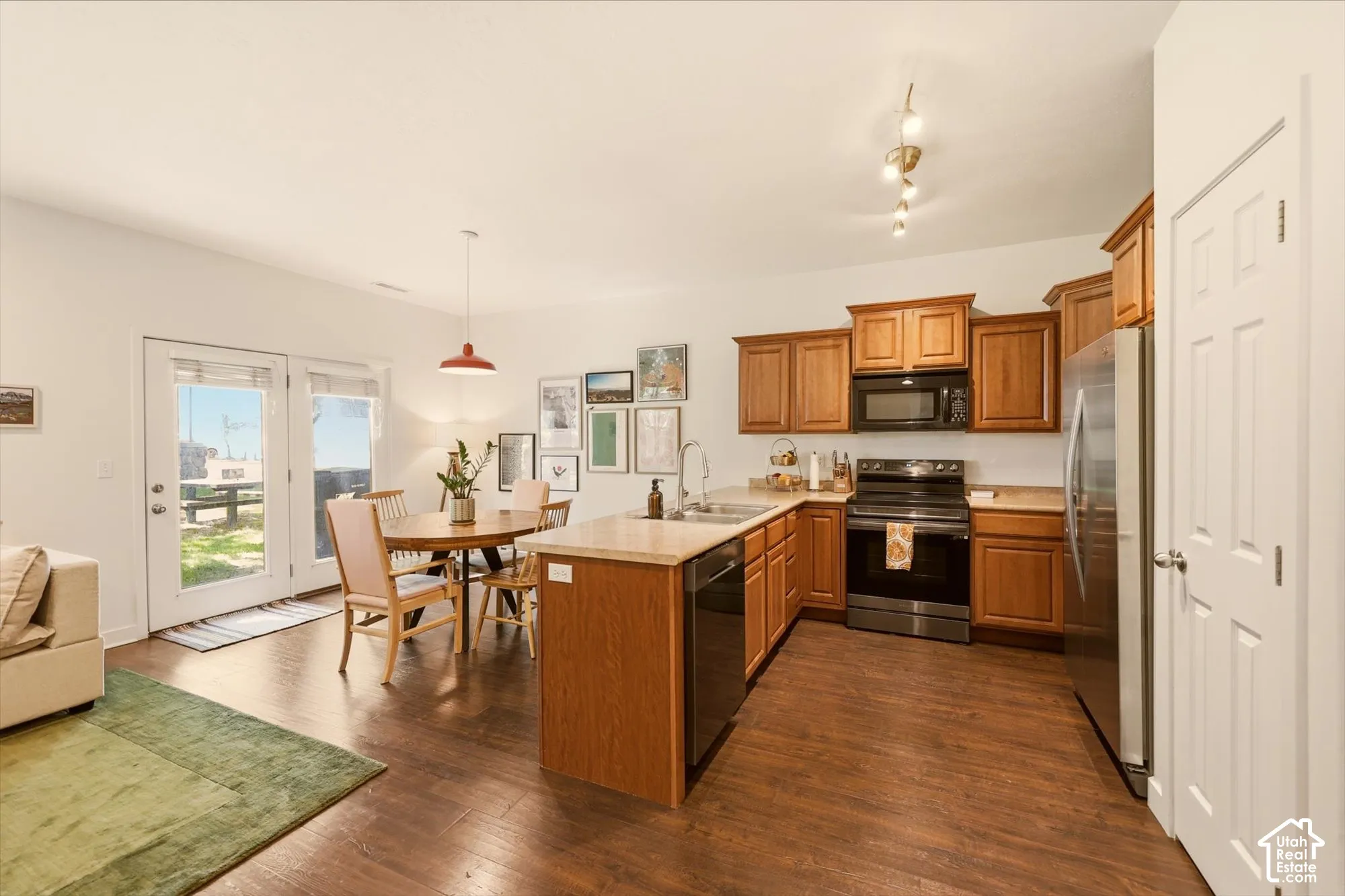Open-concept kitchen and dining area featuring wood-finish flooring, warm wood cabinetry, and stainless steel appliances