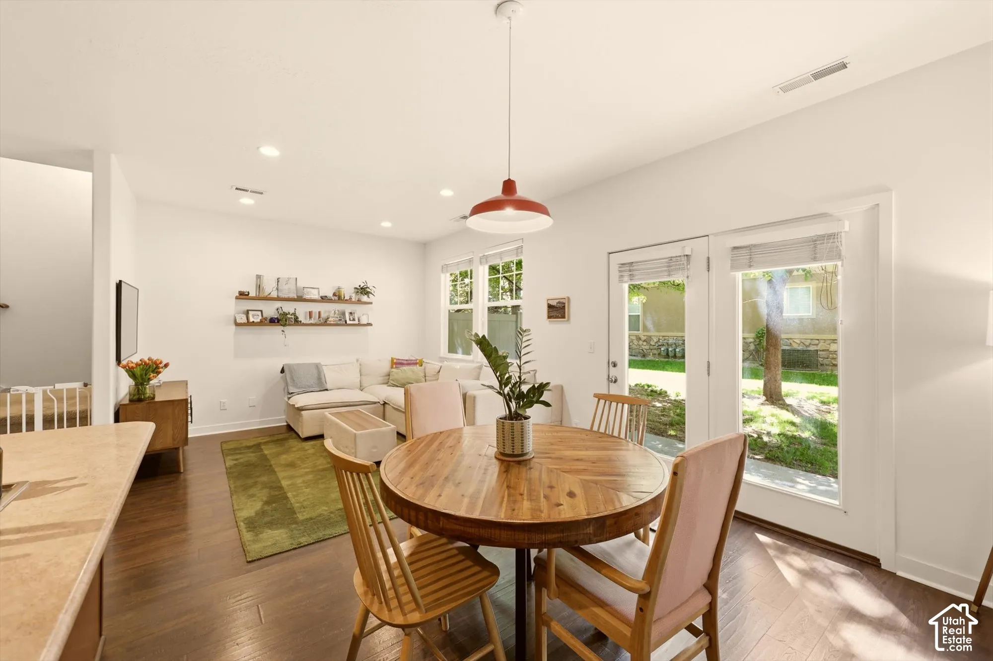 Open-concept living area featuring rich wood-finish flooring, recessed lighting, and a red pendant light fixture