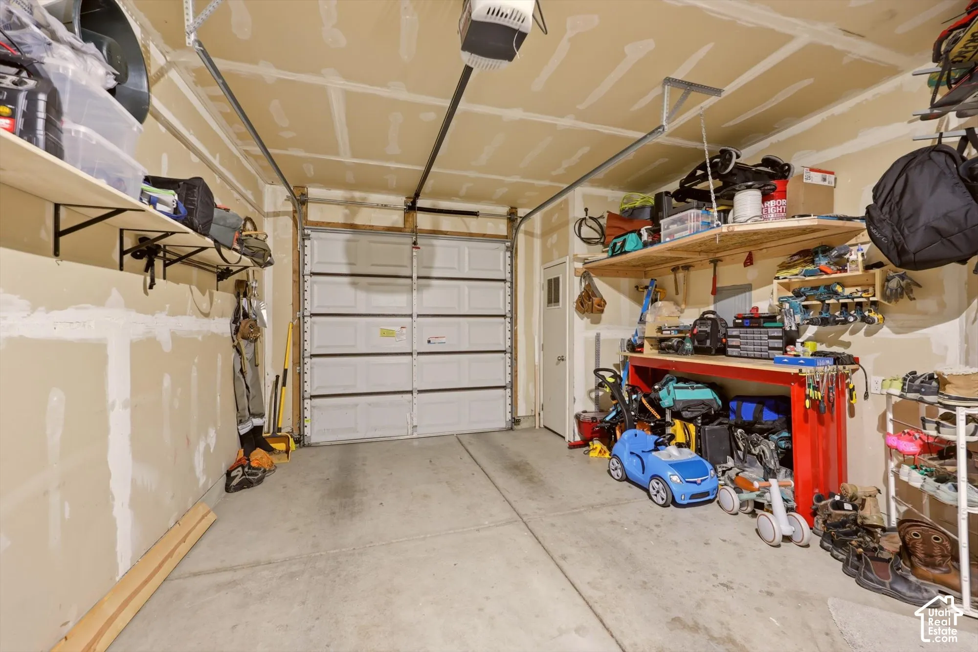 Garage featuring a white sectional door, concrete flooring, overhead garage door opener, and a side access door