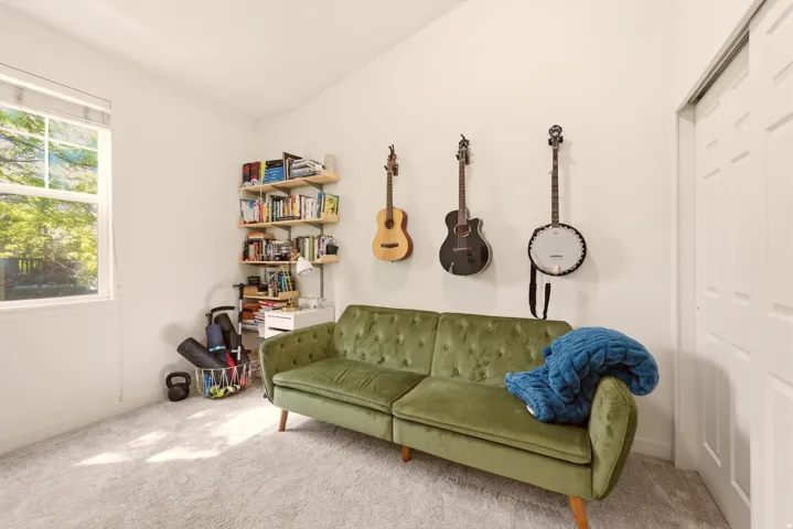 Bright room featuring a vaulted ceiling, light-toned carpet flooring, a white window frame, and bi-fold closet doors