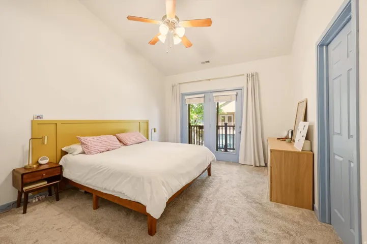 Bedroom featuring vaulted ceilings, light-colored carpeting, and a ceiling fan with integrated lighting