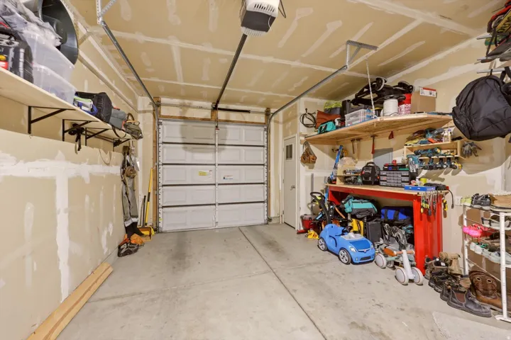 Garage featuring a white sectional door, concrete flooring, overhead garage door opener, and a side access door