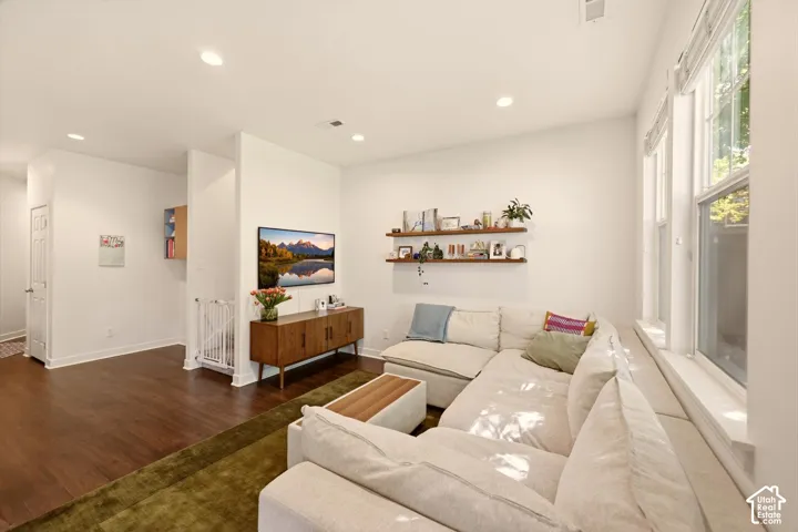 Spacious living area featuring abundant natural light, recessed lighting, wood-finish flooring, and built-in floating shelving