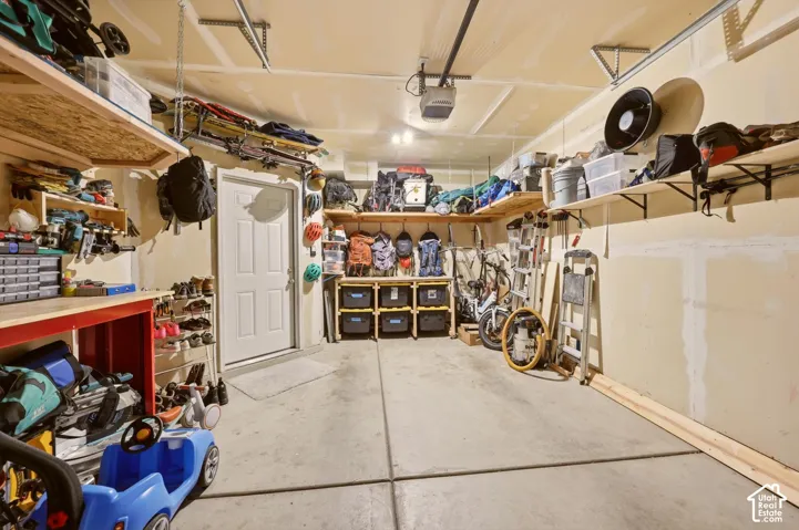 Spacious garage featuring a concrete floor, built-in shelving, a workbench, and a white access door