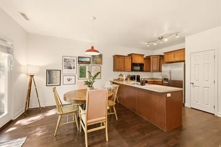 Open-concept kitchen and dining area featuring wood-finish flooring, warm wood cabinetry, and stainless steel appliances