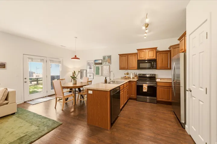 Open-concept kitchen and dining area featuring wood-finish flooring, warm wood cabinetry, and stainless steel appliances