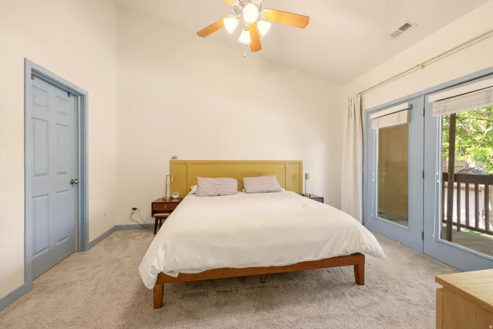 Carpeted room with a vaulted ceiling and a ceiling fan