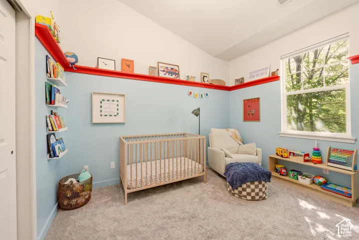 Carpeted room featuring a high vaulted ceiling, built-in wall shelving, and a large double-hung window